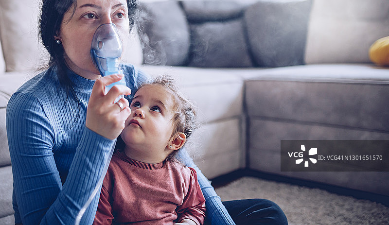 女人和她的女儿使用吸入器图片素材