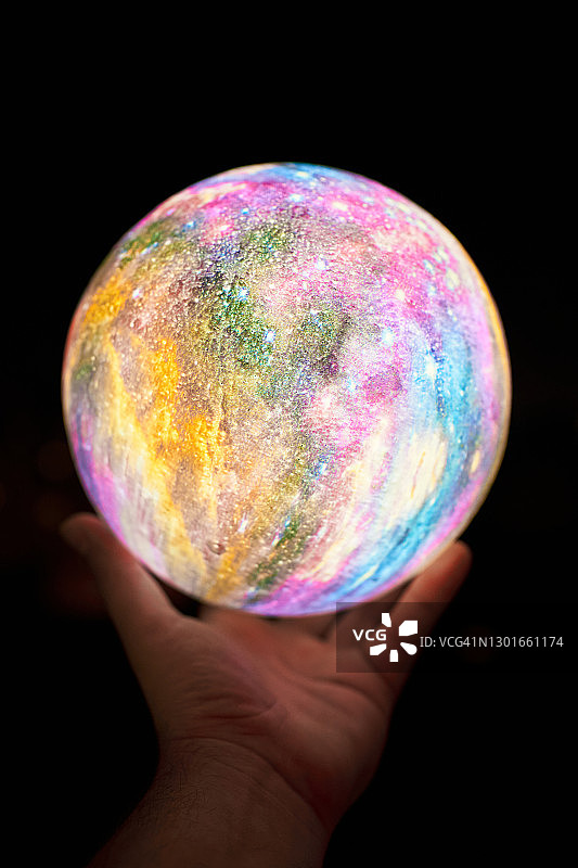 手持彩色月亮灯，黑色背景图片素材