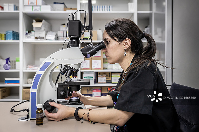 女医生在实验室用显微镜分析测试结果图片素材