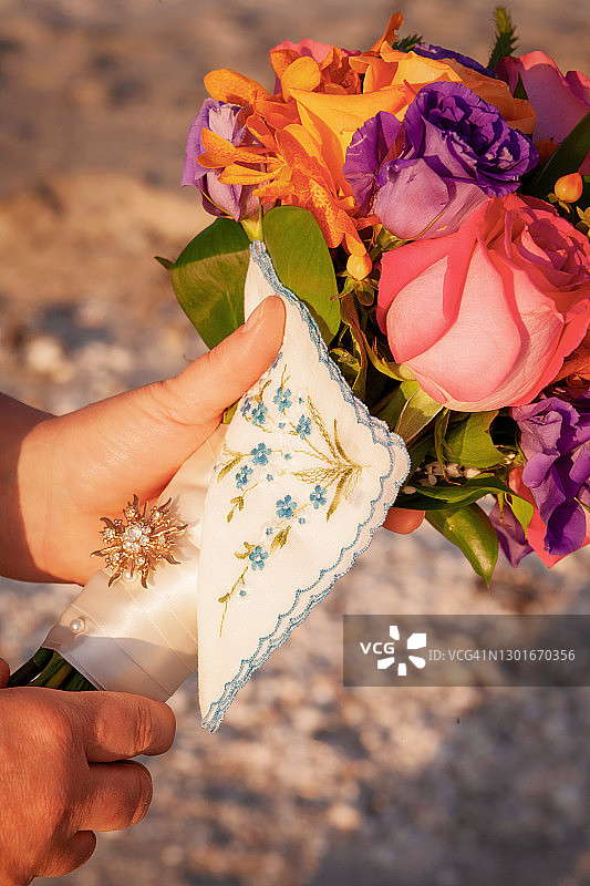 新娘手捧着她的花束，拿着手帕和吊坠图片素材