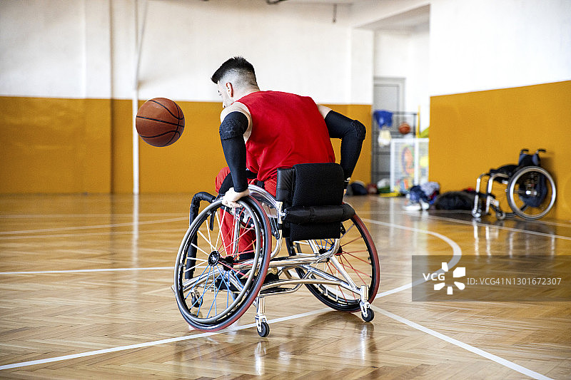 坐轮椅的男人在大厅里单独训练篮球的库存照片图片素材