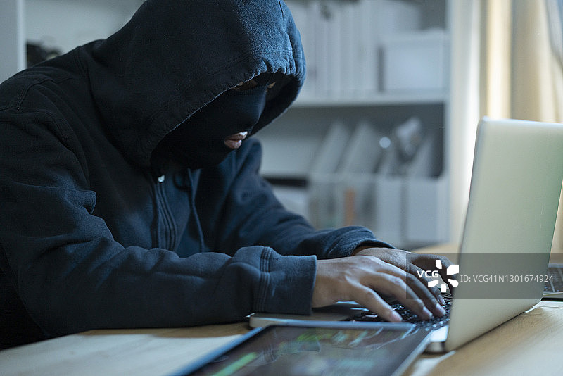 在黑暗房间里使用笔记本电脑的黑客图片素材