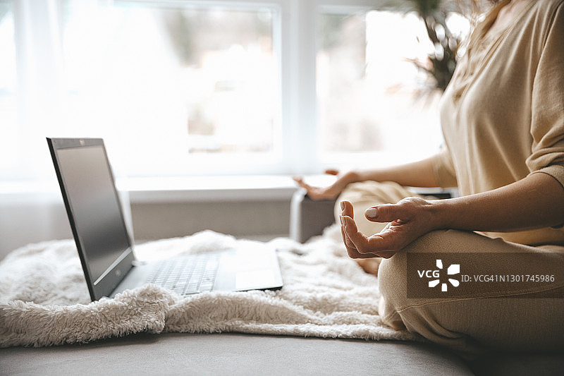 在家中客厅以莲花姿势练习冥想的漂亮微笑女人图片素材