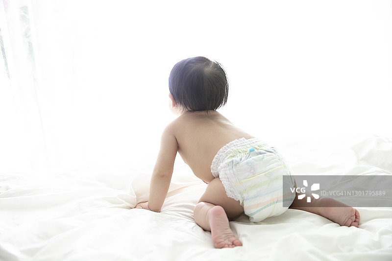 宝宝坐在床上看着窗外图片素材