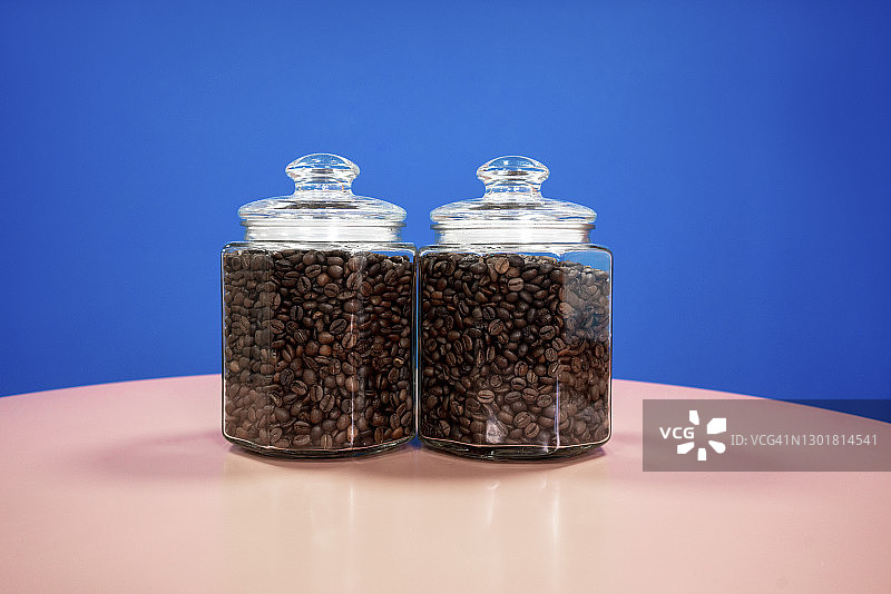 蓝色背景下的透明咖啡豆罐图片素材