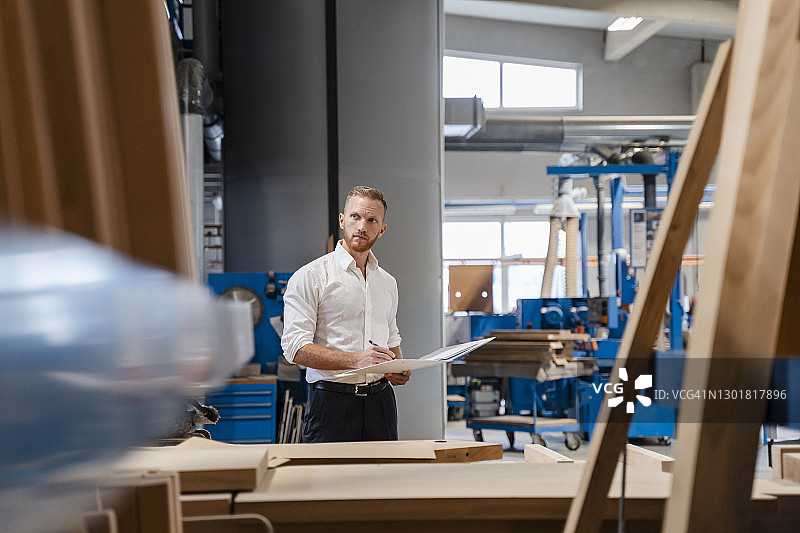 木匠站在车间手持活页夹图片素材