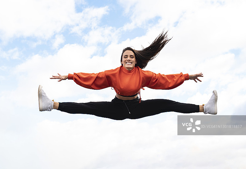 在天空背景下跳跃的美丽黑发女子图片素材
