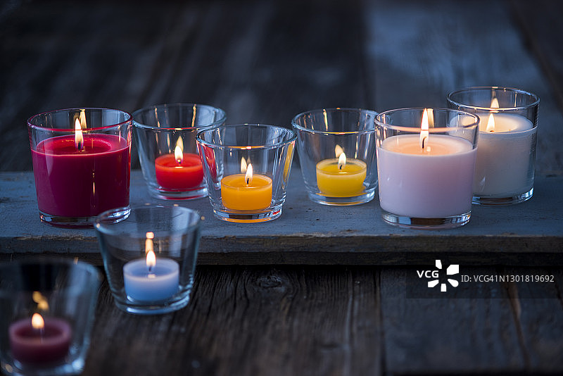 木质表面燃烧的彩色玻璃蜡烛图片素材