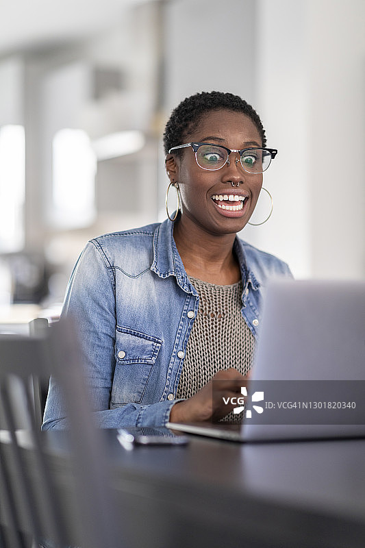 在家用笔记本电脑工作的兴奋的女人图片素材