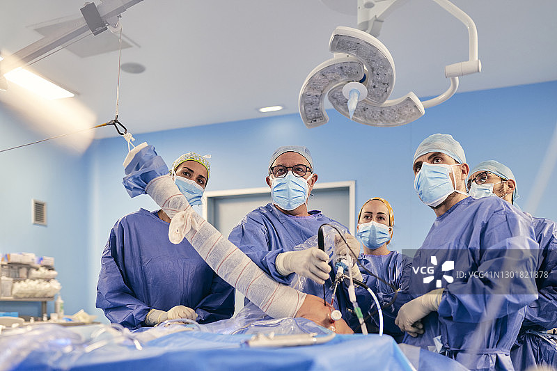 戴着口罩的外科医生在COVID-19期间在手术室进行肩关节镜手术图片素材
