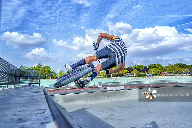 无忧无虑的年轻男子在自行车公园用自行车表演特技图片素材