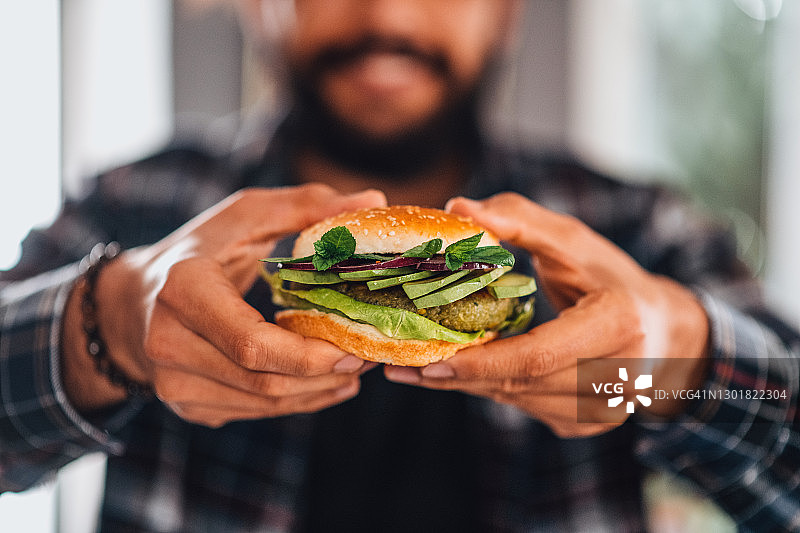 男人手拿纯素鹰嘴豆汉堡图片素材