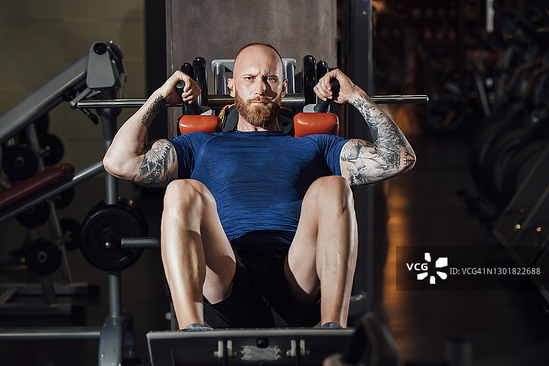 男人在健身房的哈克深蹲机上做股四头肌锻炼图片素材