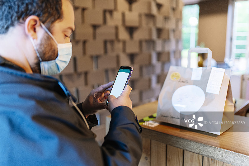 年轻男性顾客疫情期间在餐厅手机支付图片素材