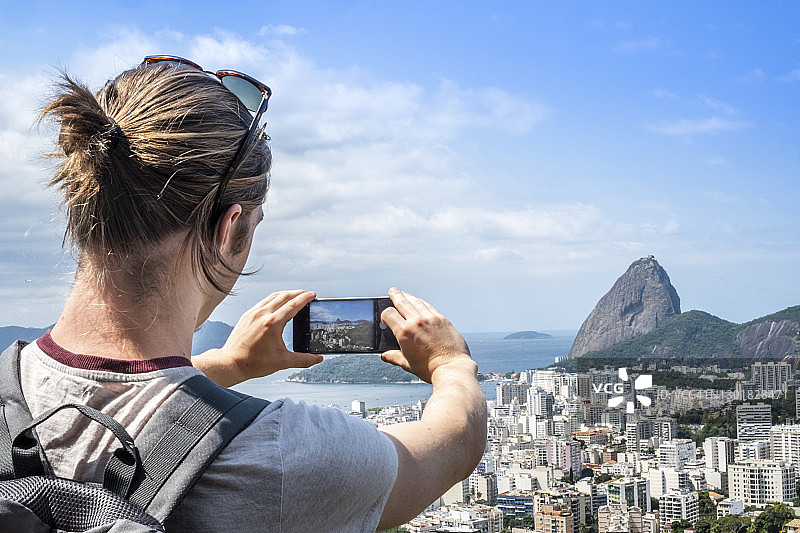 年轻男子用智能手机拍摄里约热内卢的天际线图片素材