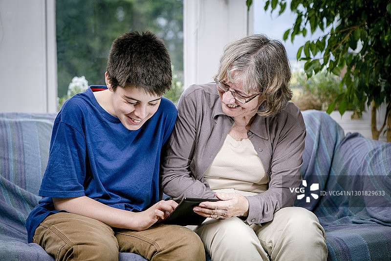 祖母和孙子在现代客厅里一起用电子桌阅读图片素材
