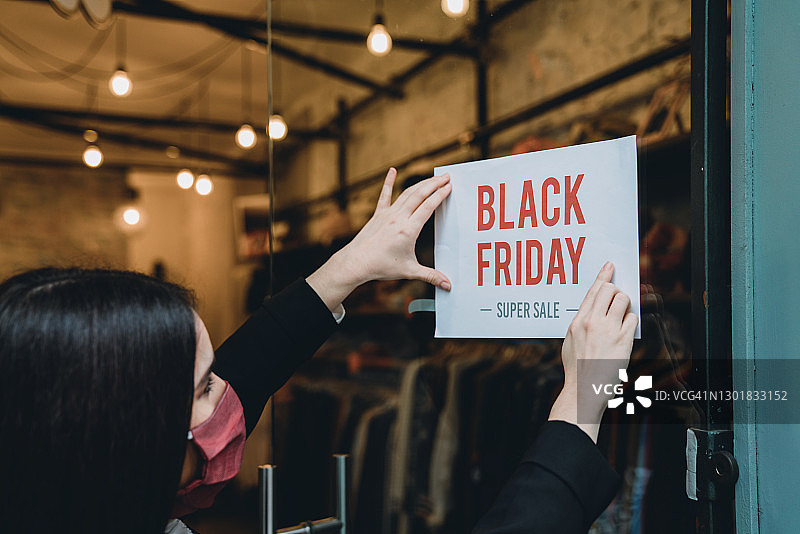 售货员在她商店的门上贴上“黑色星期五”标志图片素材