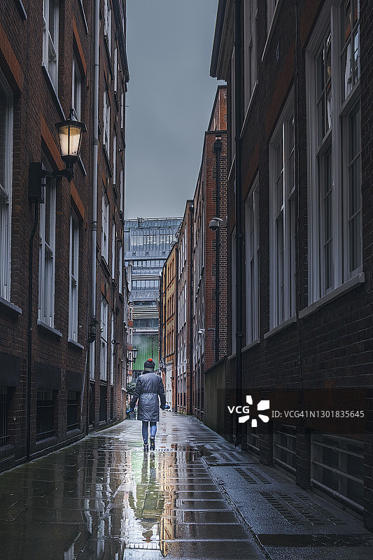 雨天，女人走在欧洲的巷子里图片素材