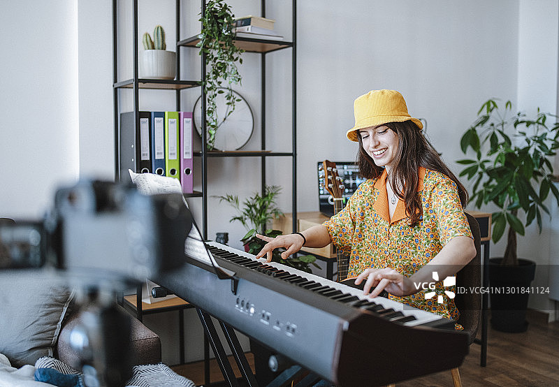 年轻女音乐家弹钢琴并用相机录音图片素材