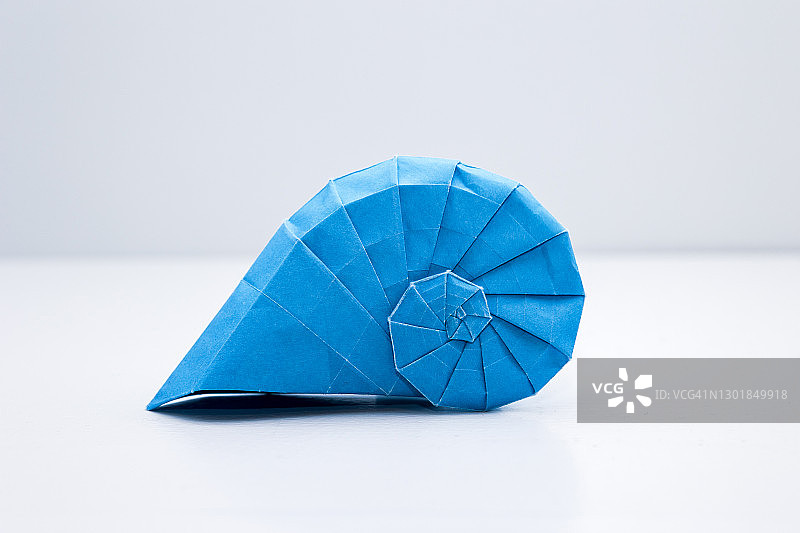 白色背景上的蓝色折纸蜗牛壳图片素材