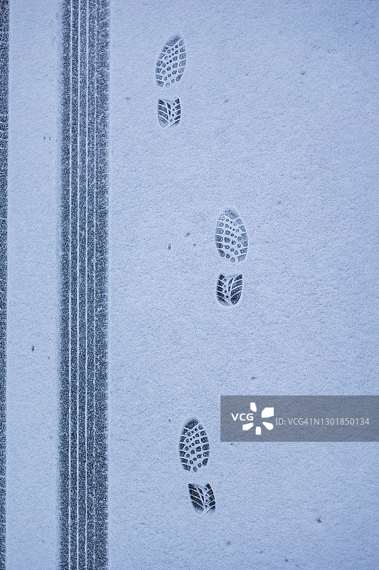 与轮胎痕迹平行延伸的多个脚印图片素材