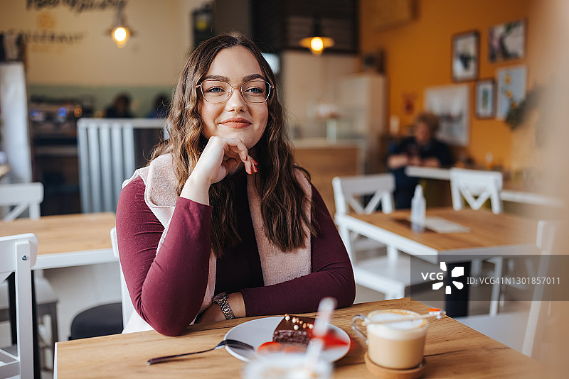 微笑的年轻女人在餐厅享用甜点图片素材