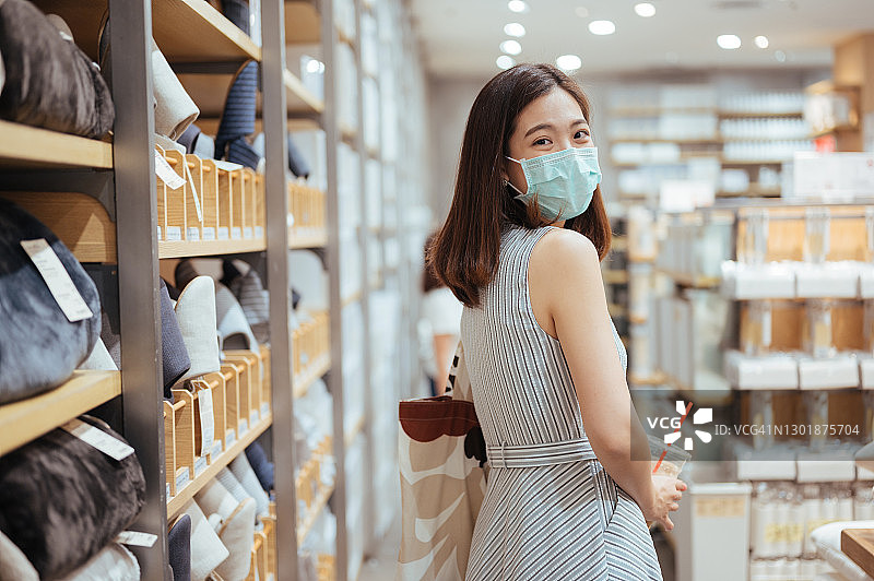 亚洲女性在购物中心戴口罩购物，手提布袋图片素材