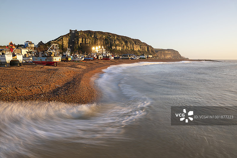 黑斯廷斯海滩上的渔船，涨潮时有海浪拍打，后面是东山，英国，欧洲图片素材