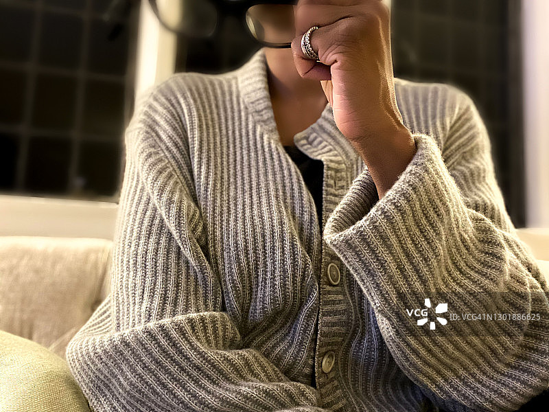 正在看电视，将眼镜举到脸上的非裔美国妇女图片素材