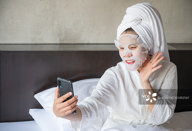 快乐女性：敷面膜，用手机提升肌肤图片素材