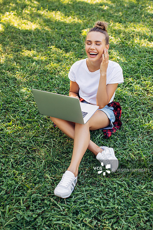 女人坐在公园里使用笔记本图片素材