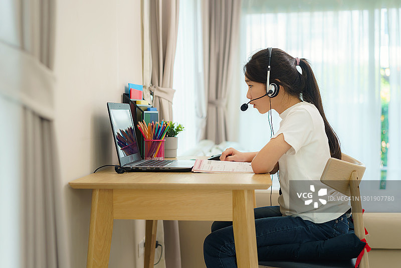 疫情期间，亚洲青少年在家通过笔记本电脑与老师在线学习数学图片素材