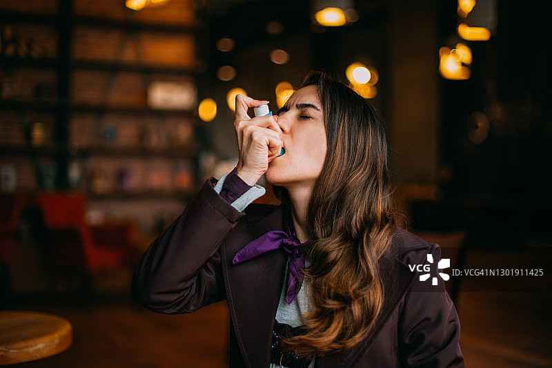 使用哮喘吸入器的年轻都市女性图片素材