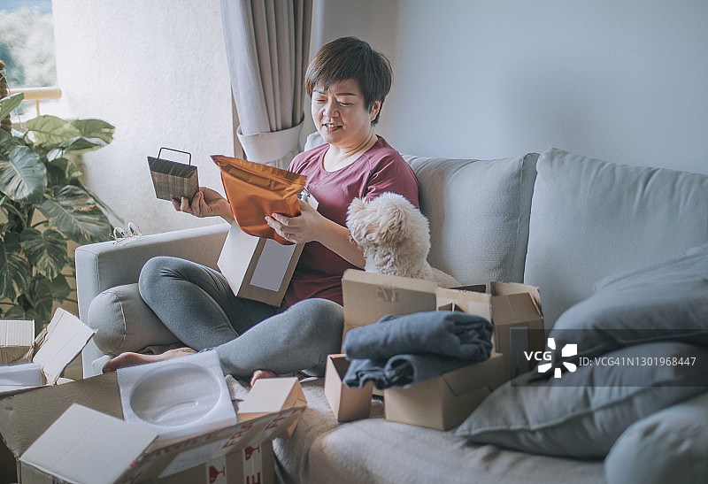 中年亚洲女性高兴地打开所有包裹图片素材