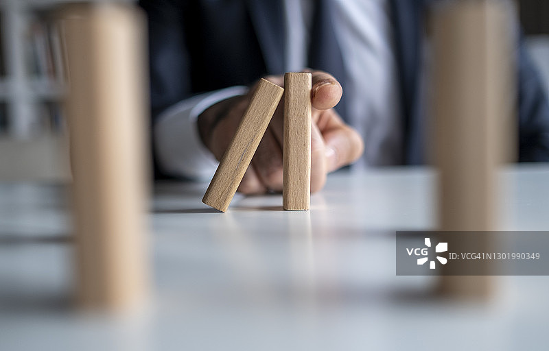 商人阻止多米诺骨牌效应：风险管理和保险概念图片素材