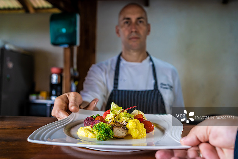 聚焦厨师给服务员的鱼片蔬菜盘图片素材