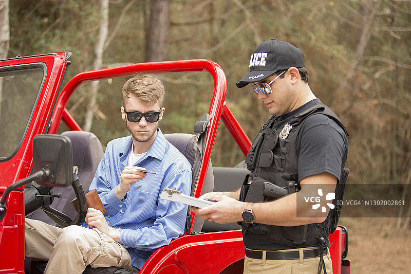 友好的拉丁美洲警察在乡村道路上拦住一位年轻人图片素材