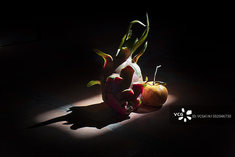 深色背景下的火龙果和橙子图片素材