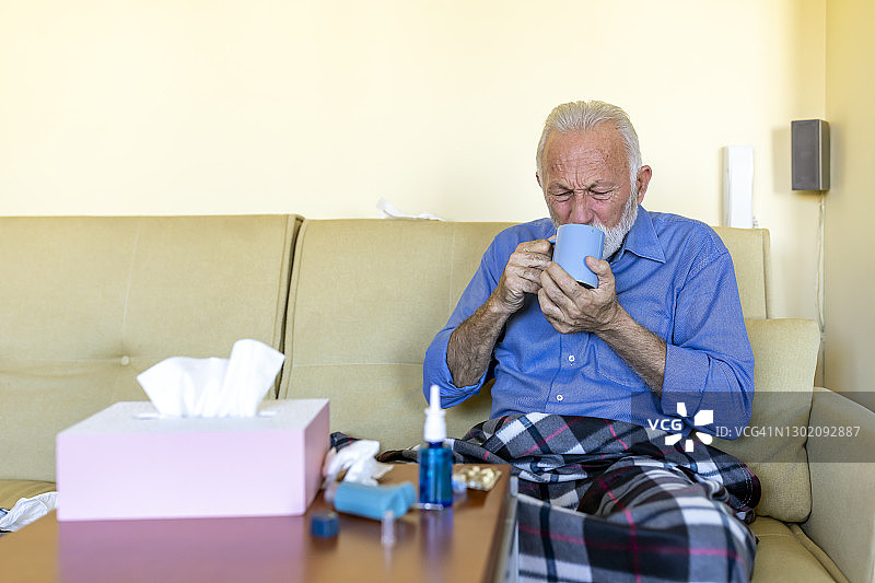 患季节性流感的男子躺在床上喝热茶恢复图片素材