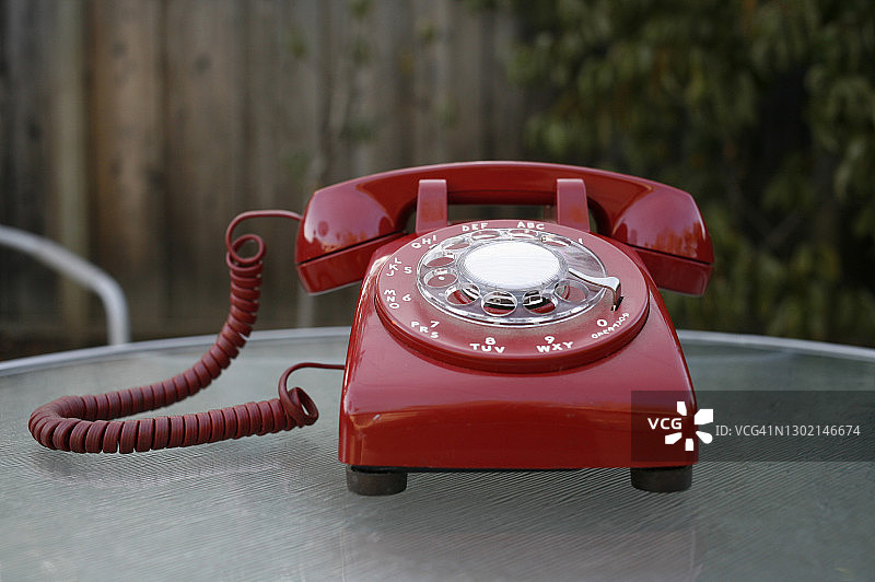 室外玻璃桌上的红色转盘电话图片素材