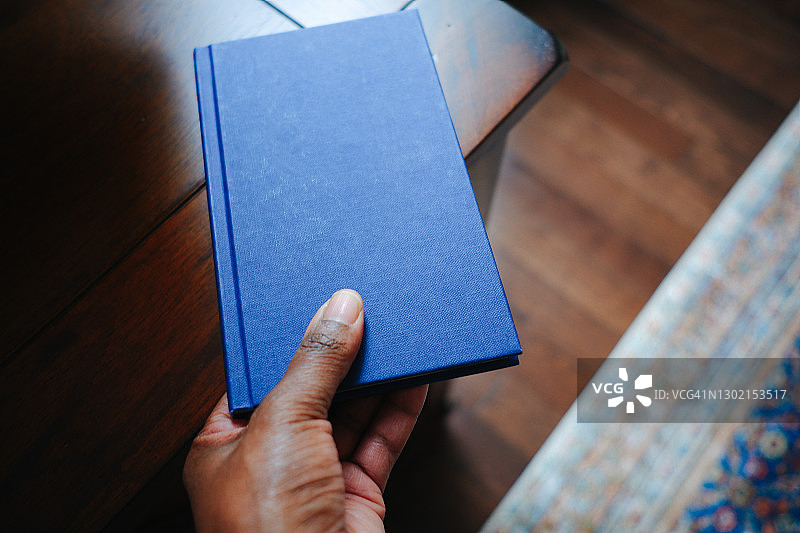 女人从桌子上拿起书图片素材