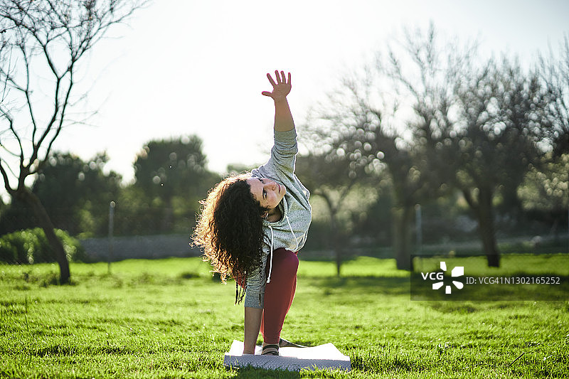年轻的棕发女子在公园里做瑜伽图片素材