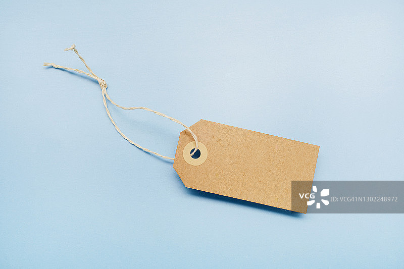 蓝色背景上的空白棕色纸质价格标签静物图片素材