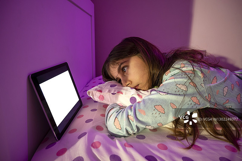 在床上使用平板电脑的小女孩图片素材
