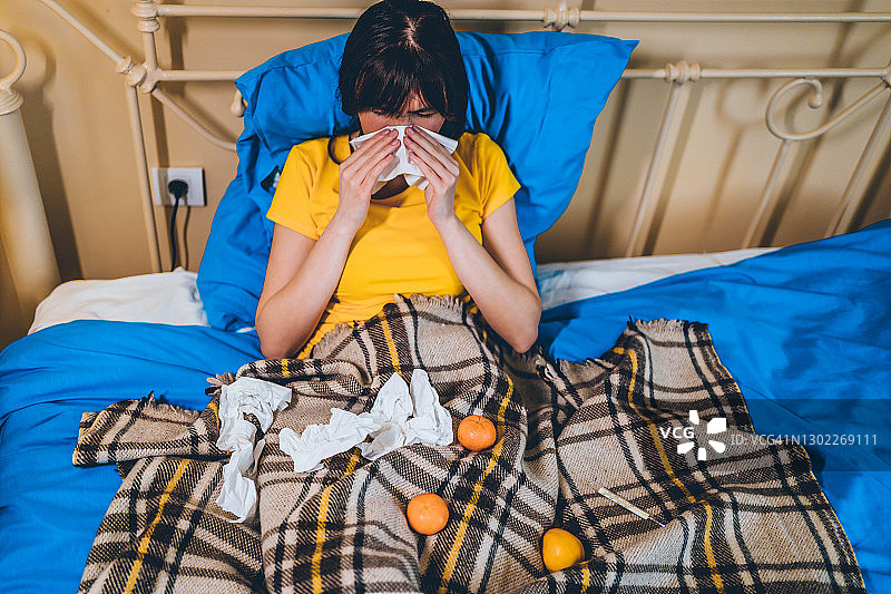 生病的女人躺在床上擤鼻涕图片素材