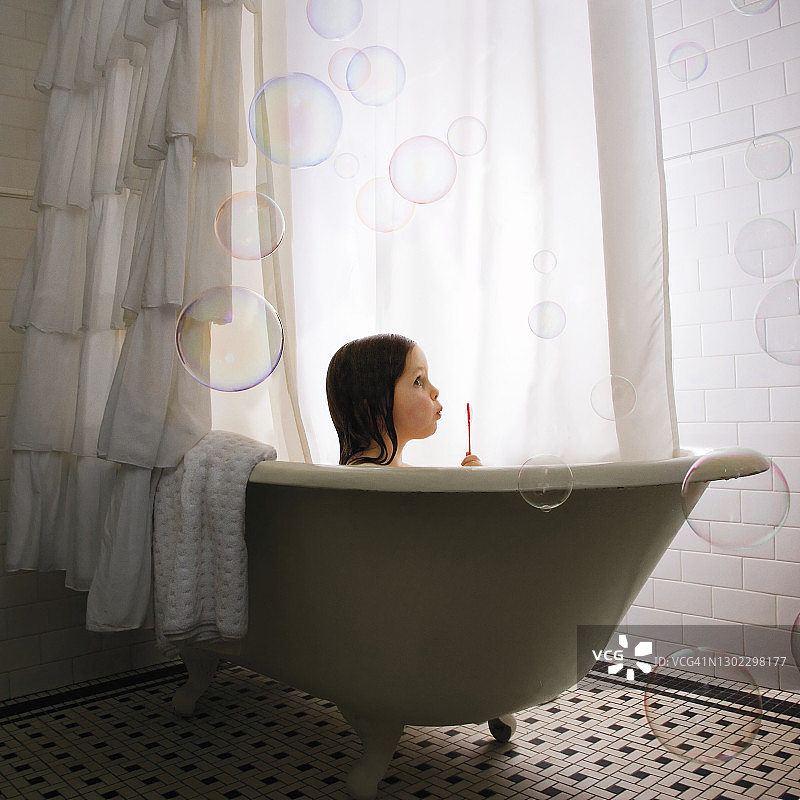 在浴缸里吹泡泡的小女孩图片素材