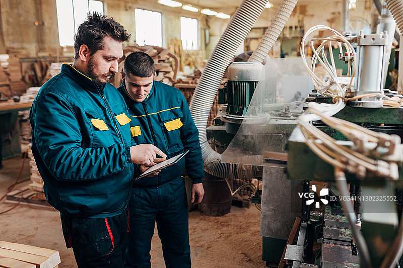 木匠在数位板上展示CNC机床的操作图片素材