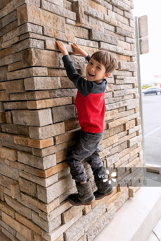小男孩爬砖墙图片素材