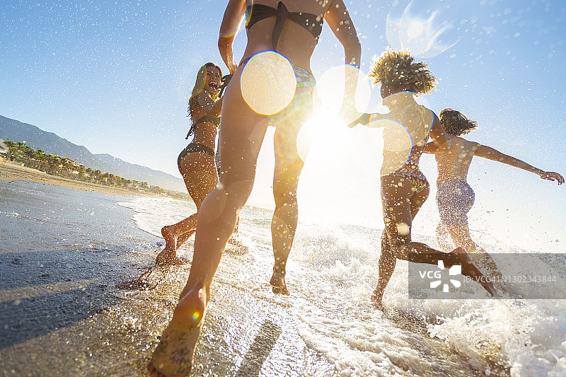 一群朋友在日落时奔跑并跳入大海图片素材