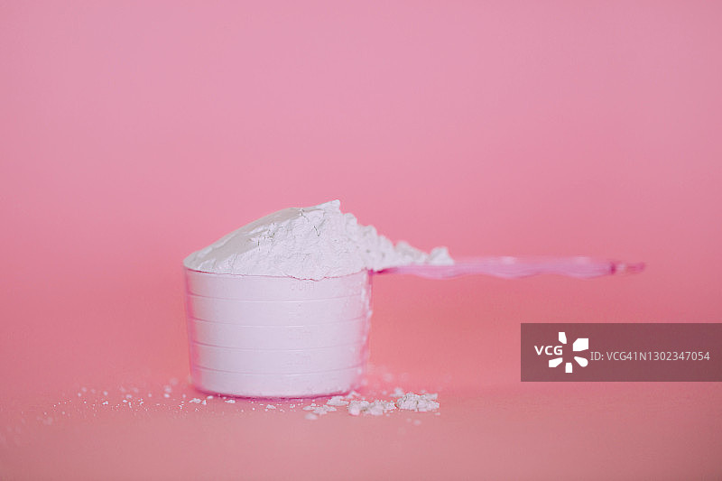 粉色背景下的量勺与胶原蛋白粉或乳清蛋白或海藻酸盐面膜 - 年度潮流产品图片素材